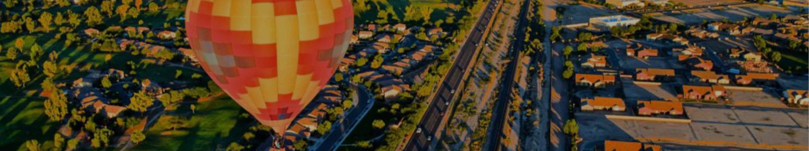 Aztec-style red and yellow hot air balloon above suburbs at evening