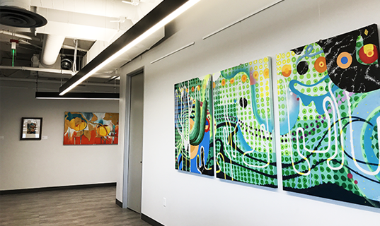 A three-panel art piece hangs on the wall of a hallway.