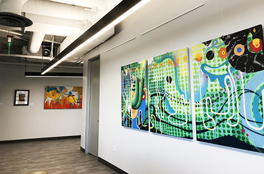 A three-panel art piece hangs on the wall of a hallway.