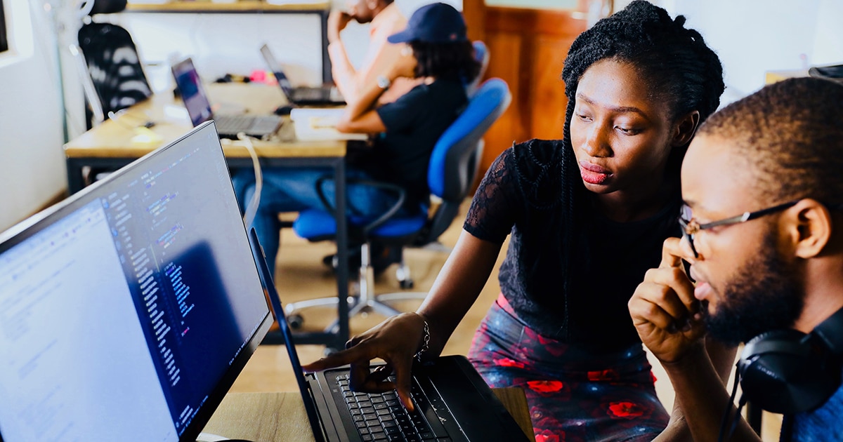 A man and a woman look at a computer screen in an office.