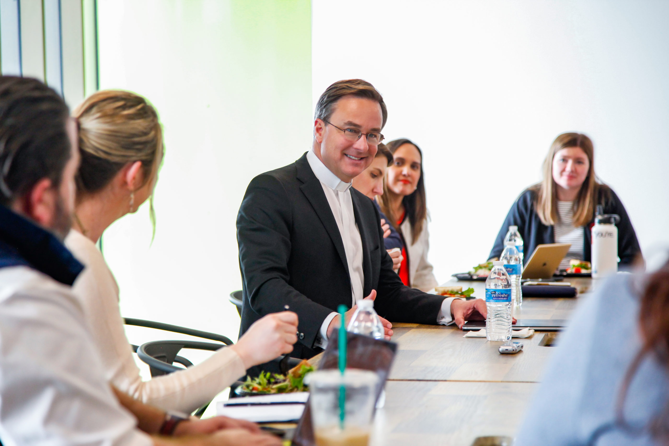 Creighton president Daniel Hendrickson sits at a conference room table speaking to members of the GPEC staff.