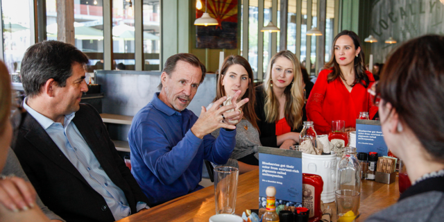 A man talks to a group of people at a large table