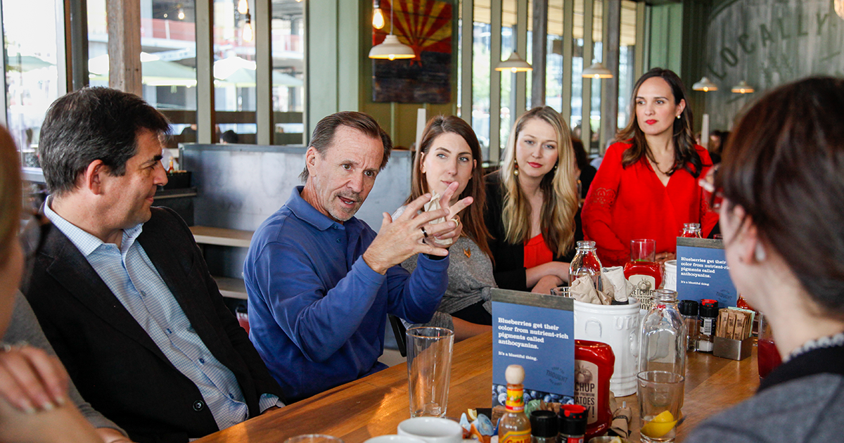 A man talks to a group of people at a large table