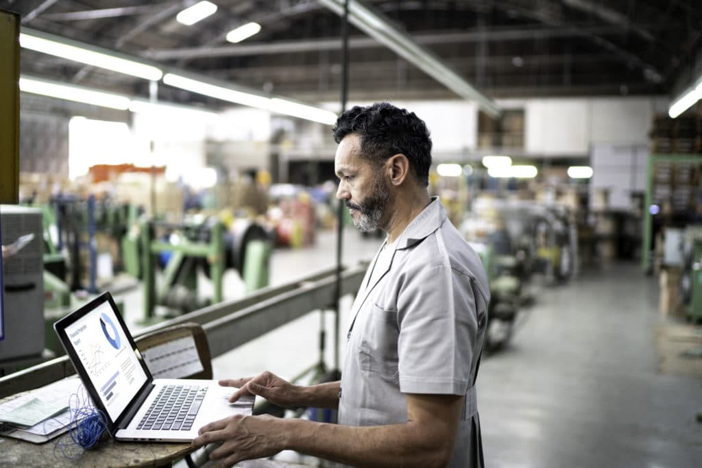 Technician using laptop while working in a factory