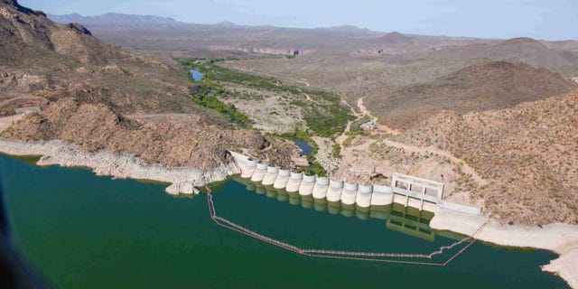 A dam blocks a large body of water from mountains