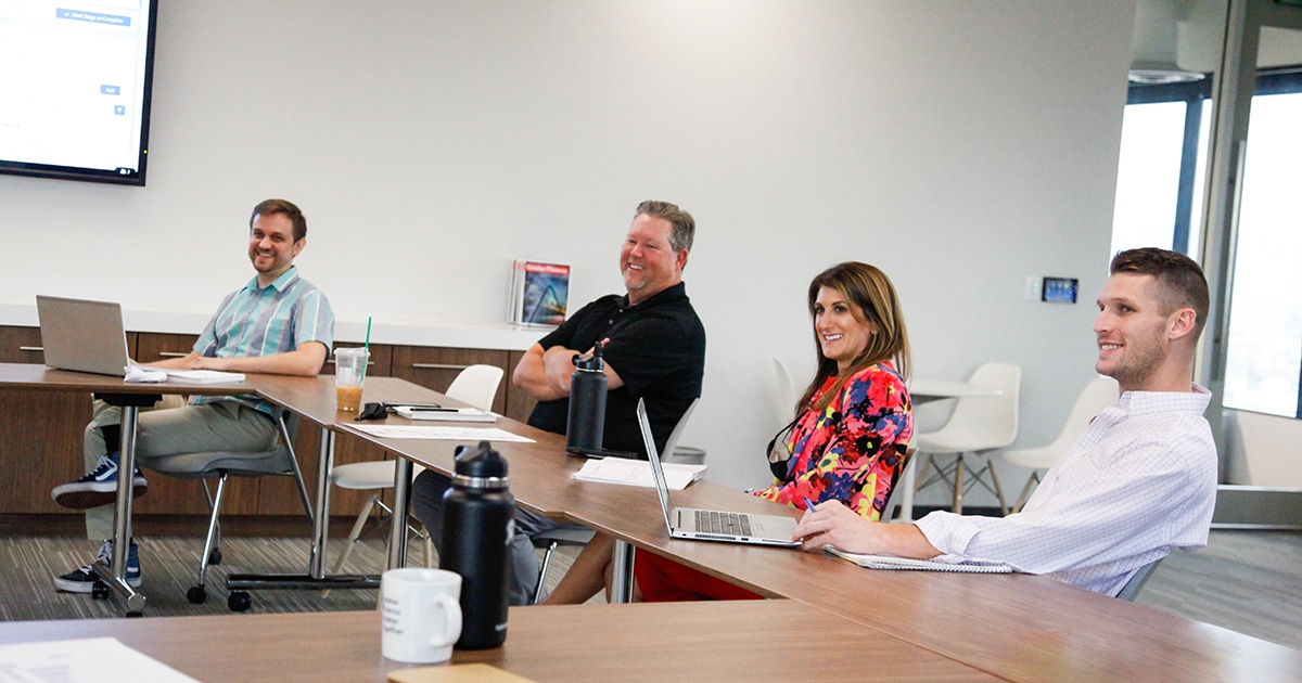 Four GPEC members sit at a long table during a meeting