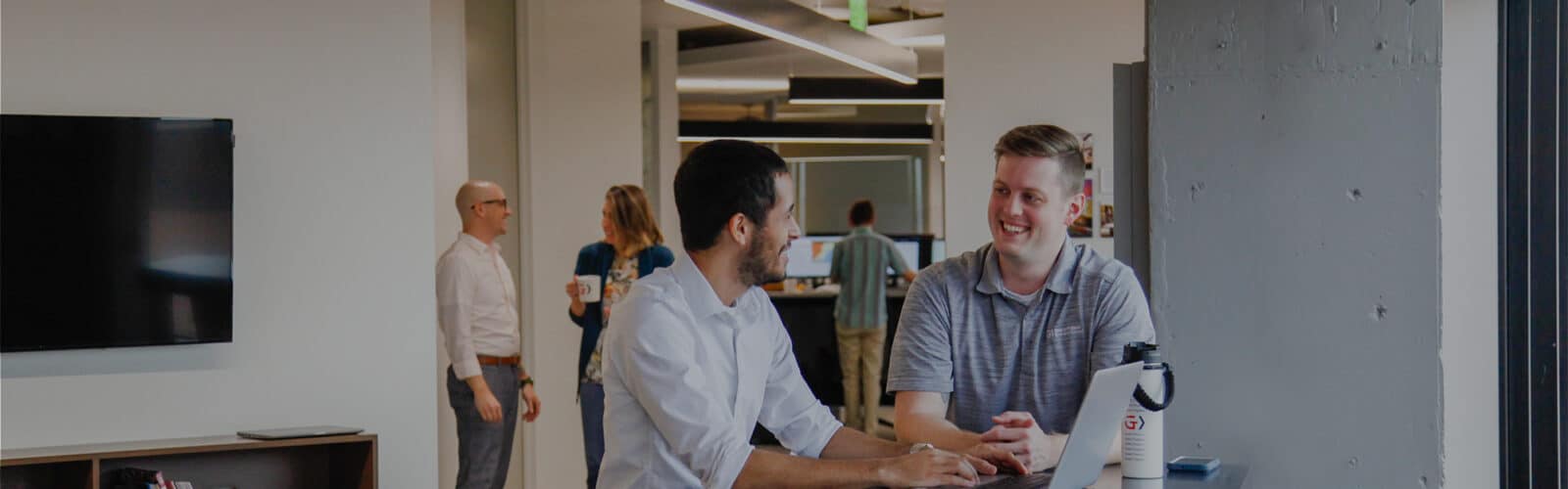 Drew Callow and Isaac Arce collaborating at a hightop table in the GPEC office.