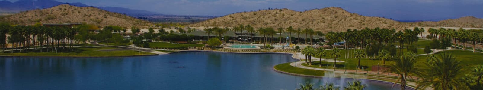 A lake with palm trees, suburbs and mountains