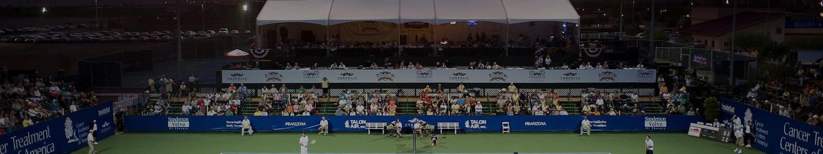 Tennis court an audience and a game in progress at sunset