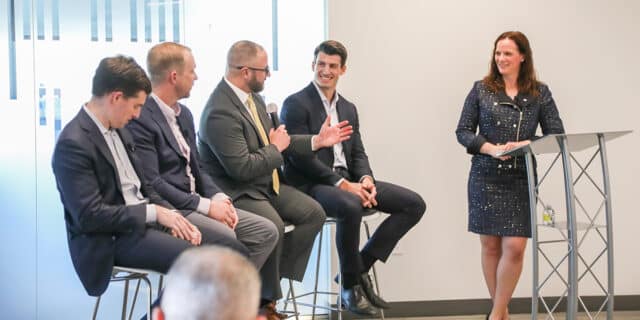 Four men speak during a panel about site selection