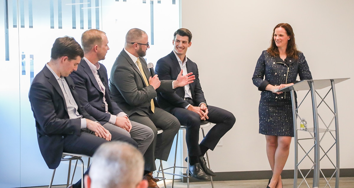 Four men speak during a panel about site selection