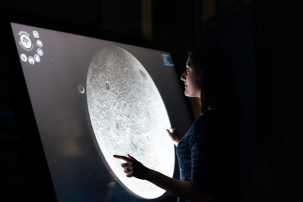 Woman analyzing detailed image of the moon projected on a screen