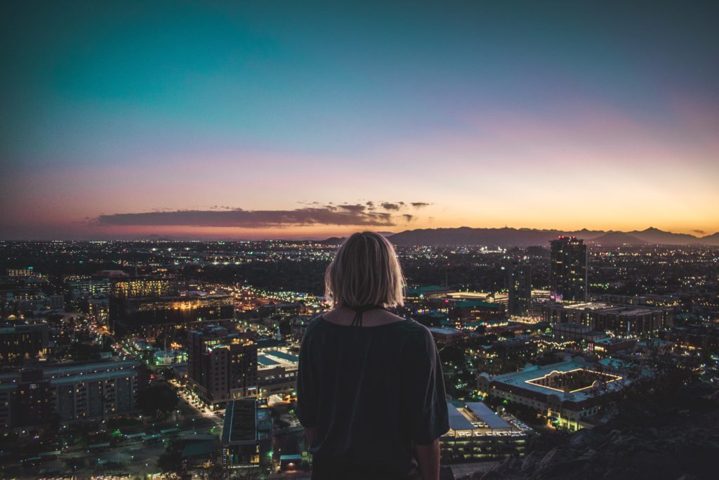 woman sitting on the edge of a hill overlooking the city of Tempe, AZ