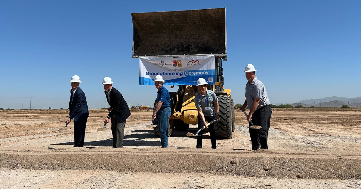 Five men scoop a pile of dirt in a ceremonial groundbreaking for Rehrig Pacific. A small excavator sits behind the group.