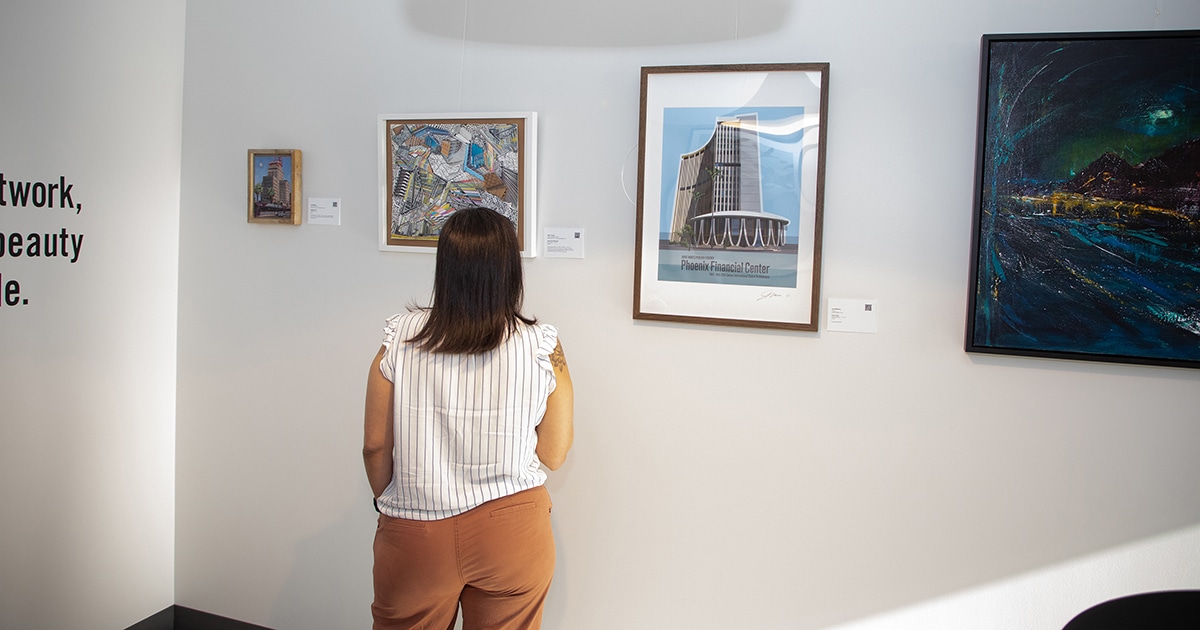 A woman looks at art pieces on a white wall.