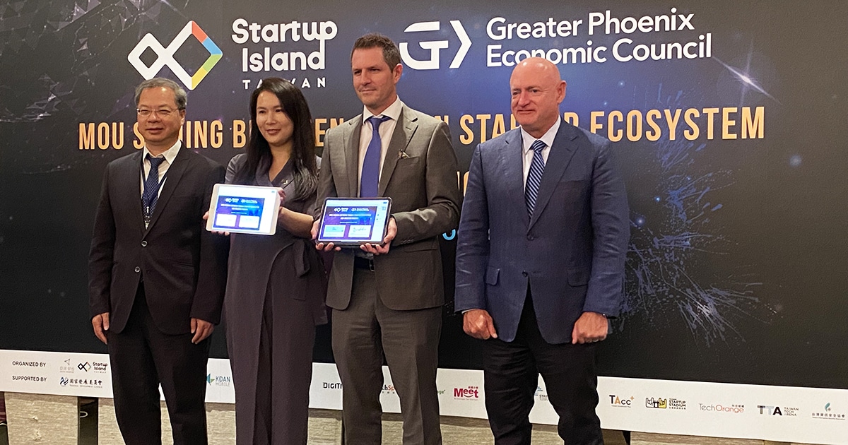 Three men and a women pose with two tablets displaying a signed MOU in front of a backdrop with Startup Island TAIWAN and GPEC logos.