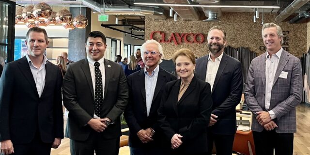 Six people pose for a picture with the Clayco logo in the background.