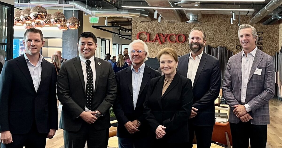 Six people pose for a picture with the Clayco logo in the background.