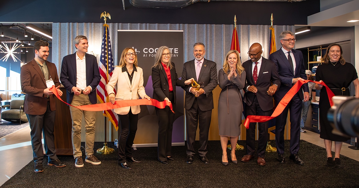 A group of men and women stand behind a red ribbon that has been cut to celebrate a grand opening.