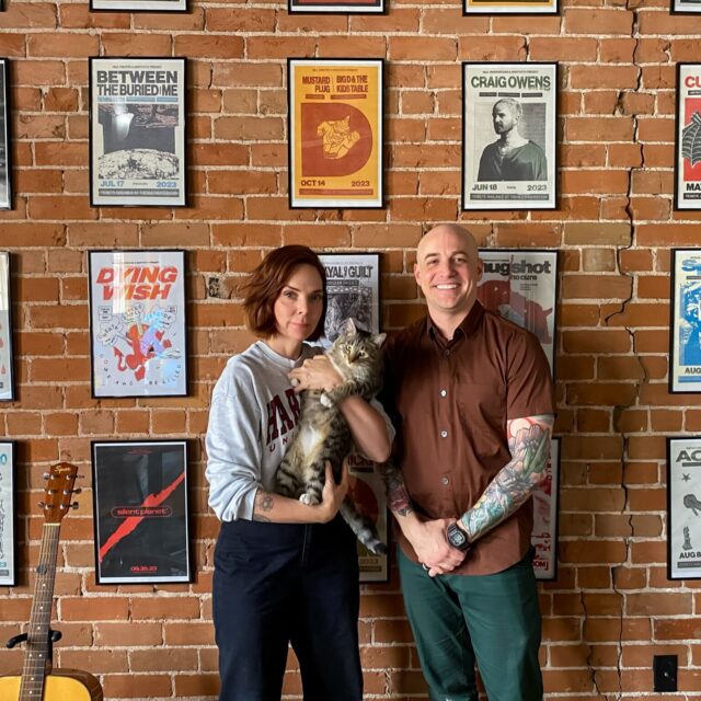 two people standing in front of music studio wall with cat