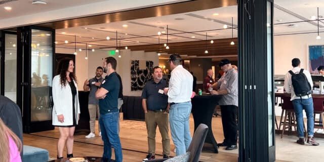 Clusters of people talk in a well-lit, modern office space.