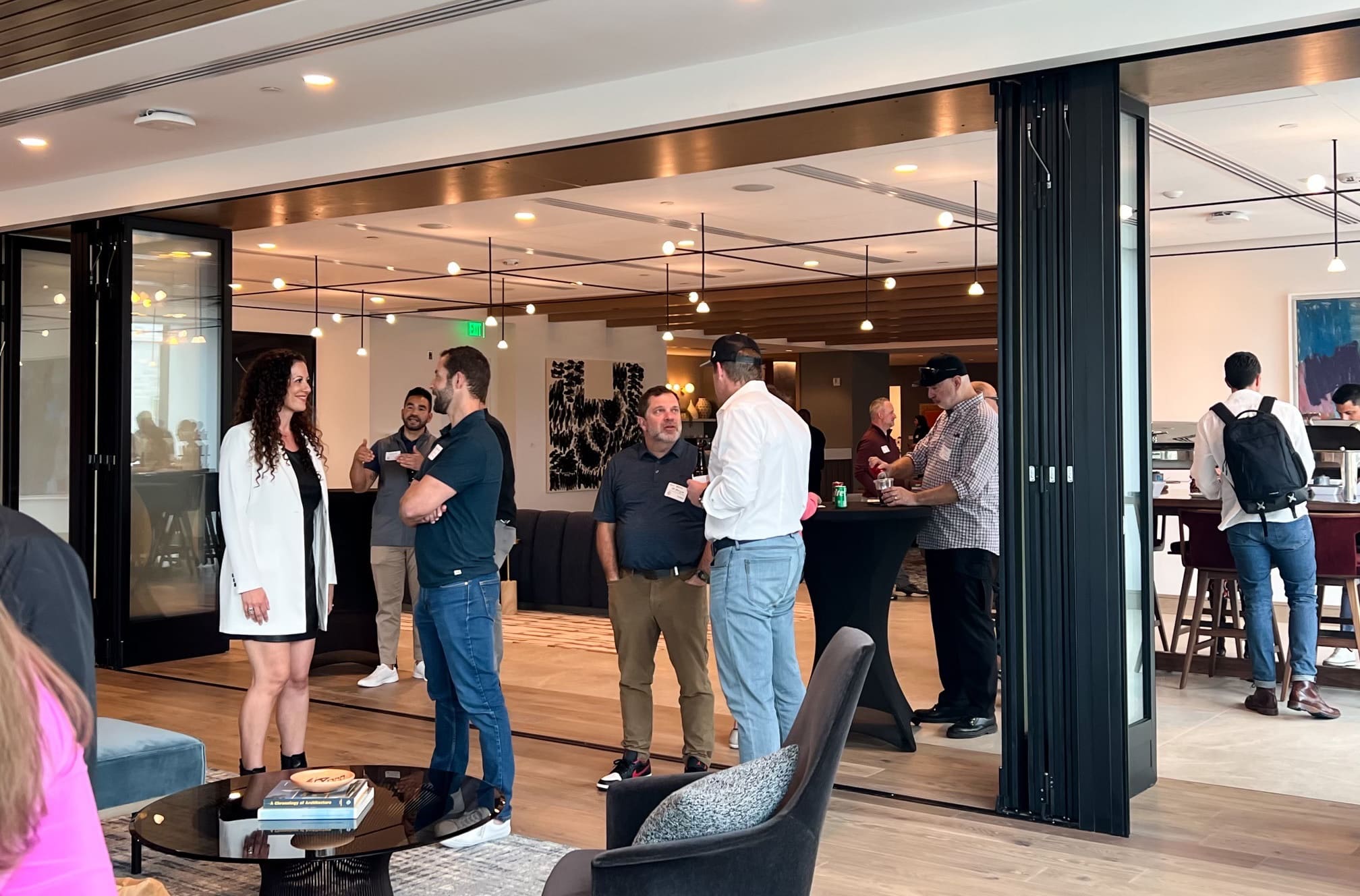 Clusters of people talk in a well-lit, modern office space.