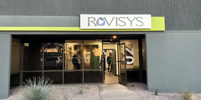 A gray building with a white-and-green sign baring the RoviSys logo.