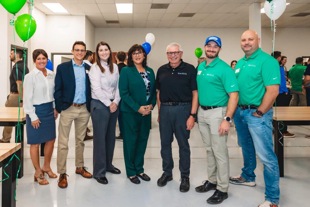 Seven people pose for a photo in an office building.