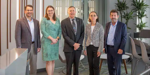Three men and two women pose for a photo.