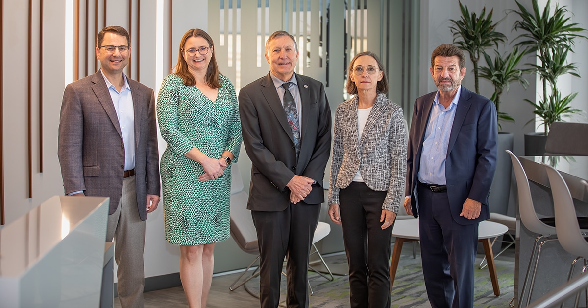 Three men and two women pose for a photo.