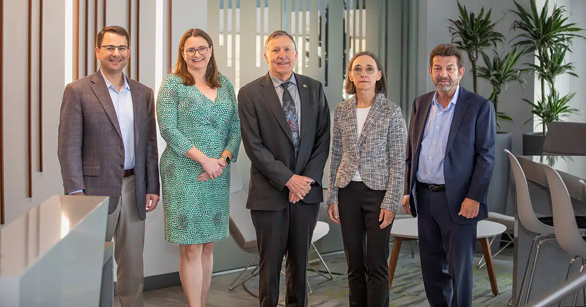Three men and two women pose for a photo.