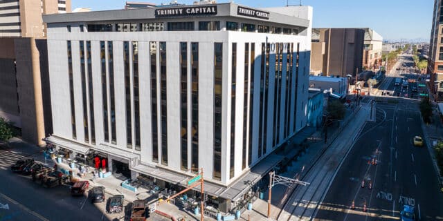 A large white office building with Trinity Capital letters on the top right of the facility.