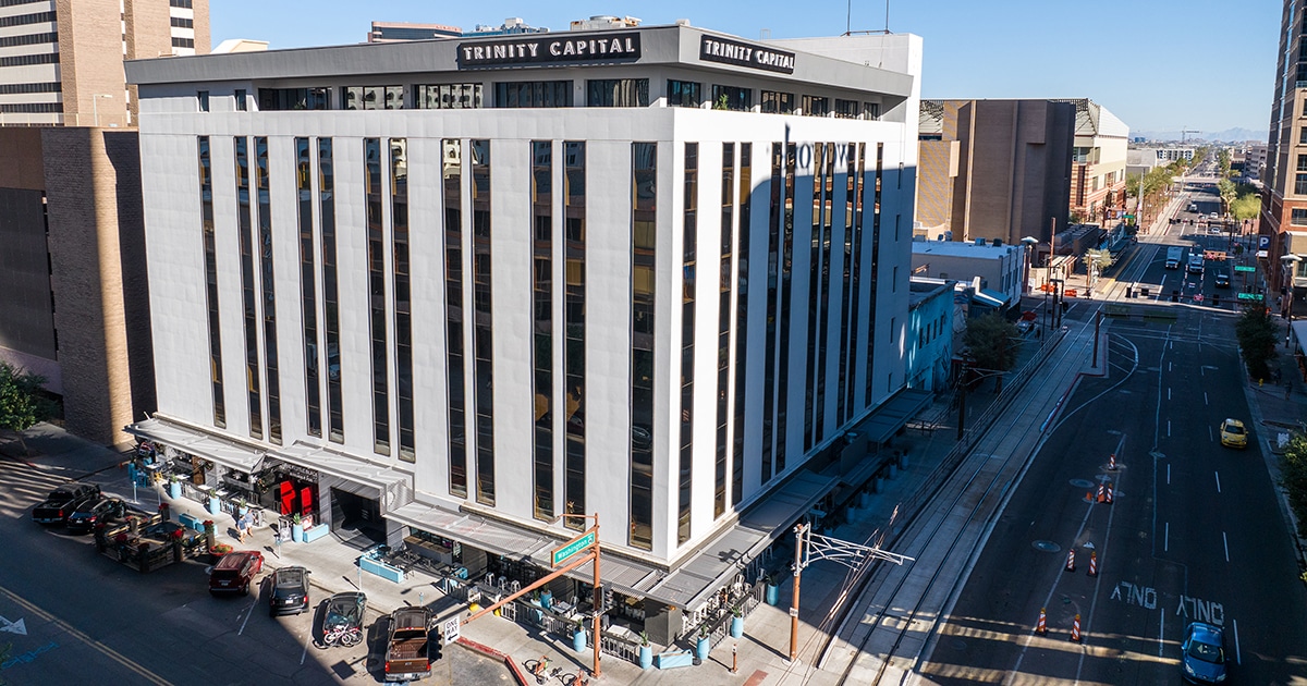 A large white office building with Trinity Capital letters on the top right of the facility.