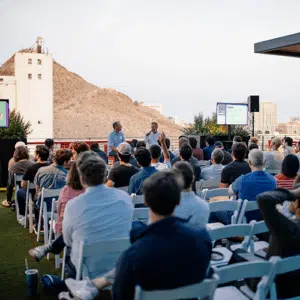 A seated audience in the foreground listens to a pair of panelists.